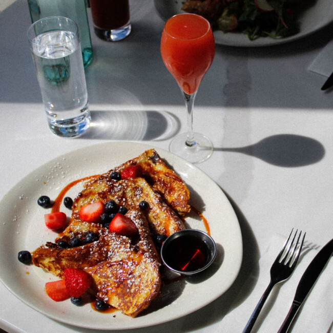 Plate with French Toast and berries, glass of water and cocktail at The Table