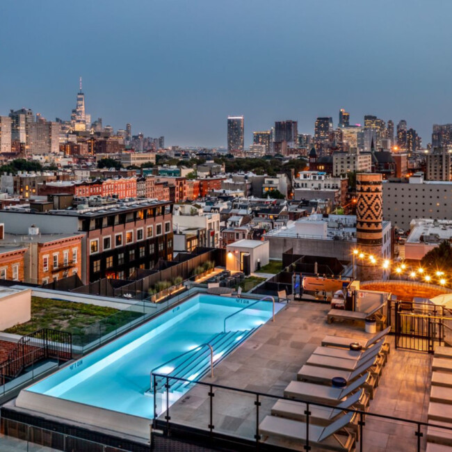 Skyline view at dusk from Wonder Lofts rooftop with pool