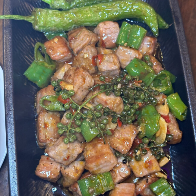 Peppercorn beef cubs on a plate with green onions and green pepper