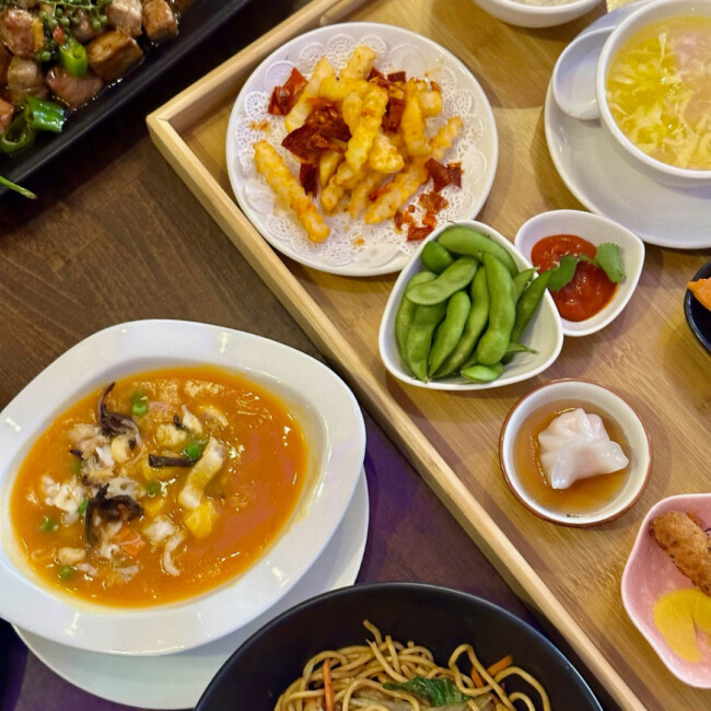 Spread of dishes at Keming Restaurant including a bowl of noodles and edamame