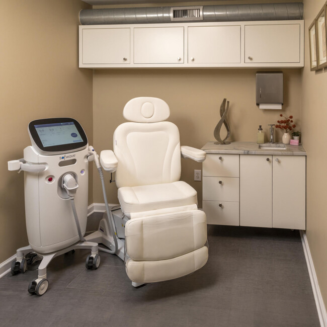 Treatment room with white chair and SofWave machine