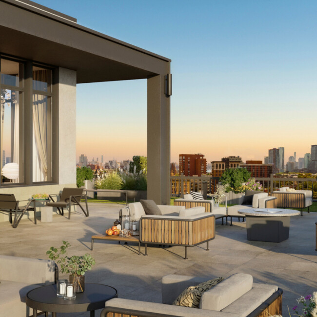 View of the roof deck at The Devan with multiple couches and plush chairs with the sunset and skyline view