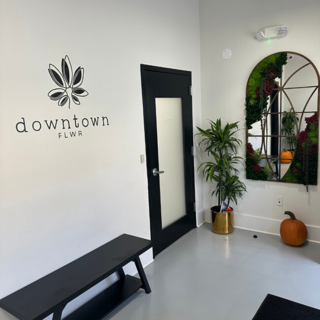 Interior room with black bench, door, and a mirror and a downtown FLWR logo on the wall