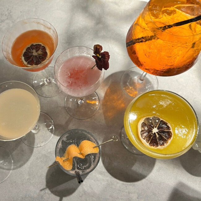 Six colorful cocktails with dried citrus and flowers as garnish