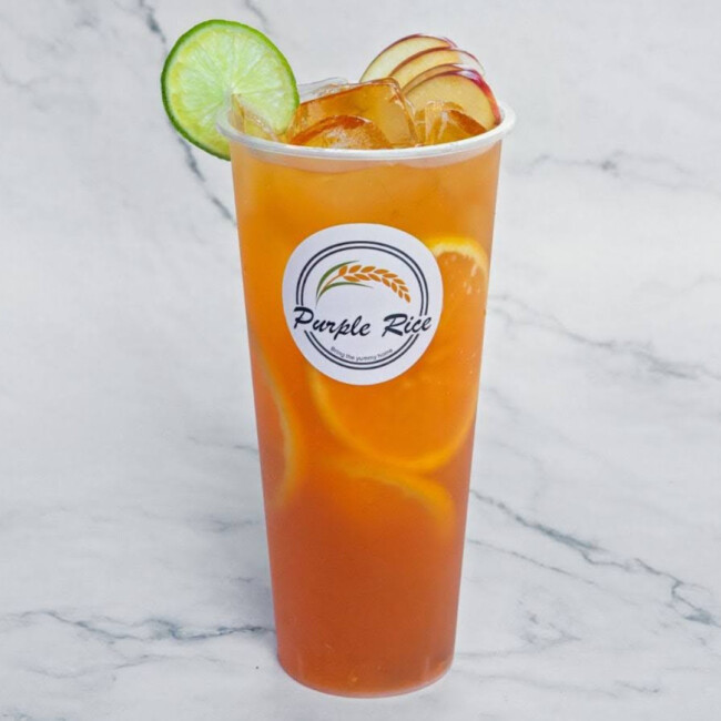 Orange tea drink with a green lime wedge on the rim