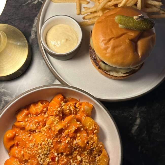 Plate of pasta and a plate with a burger and fries