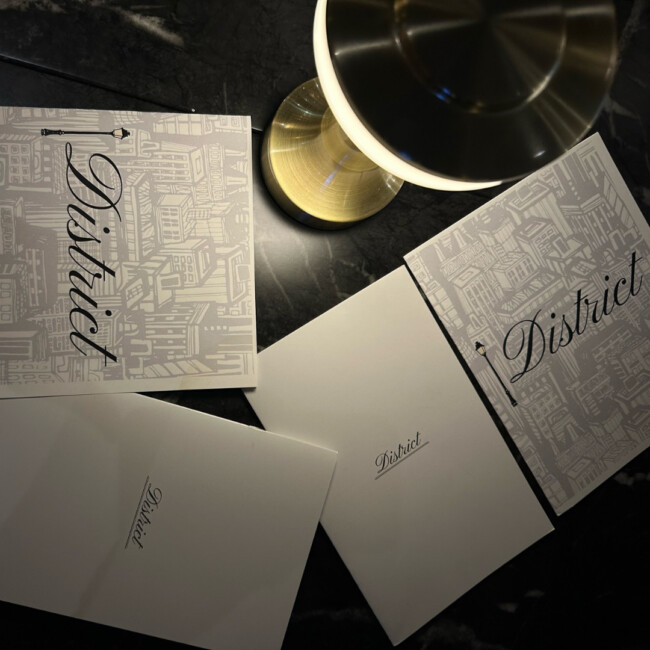 District menus next to a gold lamp on a table